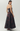 A strapless floor-length gown with a fitted waist and full skirt, shown on a model from the back against a light gray studio background. The dress has a dark floral jacquard pattern in black and deep burgundy.