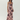 A woman modeling a sleeveless, floor-length pink maxi dress with a dark floral print, photographed against a plain light gray studio background.