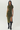 A woman modeling a short-sleeve olive green midi dress with a black floral pattern and a thigh-high slit, paired with black over-the-knee boots, against a plain light gray studio background.