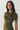 A woman wearing a short-sleeve olive green dress with a black floral pattern, photographed against a plain light gray studio background.