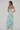 Woman wearing a floral dress with blue and green patterns on a plain background
