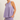 Woman wearing a purple sleeveless top and shorts set on a plain background