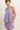 Woman wearing a purple sleeveless top and shorts set on a plain background