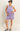 Woman wearing a lavender outfit on a plain background