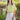 Woman wearing a yellow off-shoulder top and white skirt outdoors.