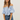 Woman wearing a light blue off-shoulder top and jeans on a plain background