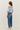 Woman wearing a light blue off-shoulder top and blue jeans on a white background