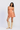 Woman wearing an orange patterned dress and beige knee-high boots on a white background