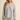A woman modeling a light heather gray knit lounge set consisting of a crewneck sweatshirt and matching shorts, photographed against a solid beige studio background.