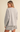A woman shown from the back wearing an oversized light heather gray knit sweater and matching shorts against a plain beige studio background.