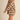 A woman modeling an oversized beige knit sweater with horizontal black stripes, featuring a high ribbed turtleneck and long sleeves, paired with black boots against a solid beige background.