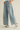 Light blue jeans with pearl embellishments worn by a person on a beige background