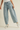 Light blue jeans with decorative studs worn by a person on a beige background