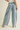 Light blue denim pants with decorative studs on a beige background