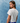 Woman wearing a white t-shirt and blue patterned pants against a textured blue background