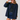 A woman modeling a navy blue button-front overshirt with brown collar and cuff trim, worn over a black top and denim skirt, while wearing a navy baseball cap with white text.