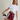 A woman modeling a white cropped t-shirt and burgundy athletic shorts with white side stripes, holding up a black and white striped athletic sock against a plain beige studio background.
