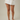 A model wearing a white denim mini skirt with pleated details and front pockets, paired with clear-strap heeled sandals, against a neutral beige background.