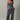 A woman modeling a matching two-piece set with a navy and white striped strapless crop top and wide-leg drawstring pants, photographed against a neutral light gray studio background.