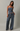 A woman modeling a matching two-piece set with a navy and white striped strapless crop top and wide-leg drawstring pants, photographed against a neutral light gray studio background.