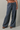 A person wearing loose, wide-leg pants with navy and white horizontal stripes, shown from the waist down against a plain light gray studio background.