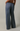 A person wearing loose, wide-leg pants with horizontal navy and white stripes, shown from the back against a plain light gray studio background.