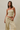 Woman wearing a yellow and white striped strapless top and pants against a beige background