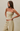 A woman modeling a matching two-piece set featuring a strapless tube top and drawstring pants, both in a yellow and white striped pattern, set against a plain beige studio background.
