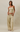A woman modeling a matching two-piece lounge set featuring a strapless tube top and wide-leg drawstring pants, both in a beige and olive green striped pattern, set against a plain beige studio background.