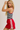 Woman wearing a black and white striped tank top and red skirt with white stripes on a beige background