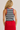 Person wearing a black and white striped tank top with red trim and a red skirt on a plain background