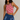 Woman wearing a red and white striped tank top and blue denim skirt against a neutral background