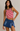 Woman wearing a red and white striped tank top and blue denim skirt against a neutral background