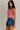 Woman wearing a red and white striped tank top and blue denim skirt on a plain background