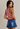 Woman wearing a red and white striped tank top and blue denim skirt on a neutral background