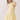 Woman wearing a yellow lace dress against a plain background