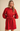 A woman modeling a bright red long-sleeve shirt dress with a tie waist belt, button front, and puffed shoulders against a plain beige studio background.