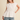 Woman wearing a white blouse and denim shorts on a beige background