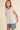 Woman wearing a white sleeveless top and denim shorts on a beige background