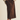 A person wearing a brown corduroy midi skirt with front patch pockets, styled with a beige ribbed knit sweater and brown flat shoes against a plain light beige studio background.