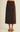 A dark brown corduroy midi skirt with front patch pockets, shown on a model wearing brown suede mule flats against a light beige studio background.