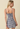 Woman wearing a blue and white checkered dress against a beige background
