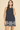 Woman wearing a navy dress with white lace details on a beige background