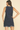 Woman wearing a navy dress with white trim on a beige background