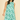 Woman wearing a green leaf-patterned dress on a beige background