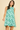 Woman wearing a green leaf-patterned dress on a beige background
