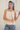Woman wearing a beige lace top and blue jeans with a blue bonnet against a white background
