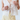 Person wearing a white lace top and light yellow pants against a plain background