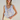 Woman wearing a light blue floral sleeveless top and yellow shorts against a white wall.