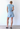 Person wearing a patterned shirt and denim shorts against a white background